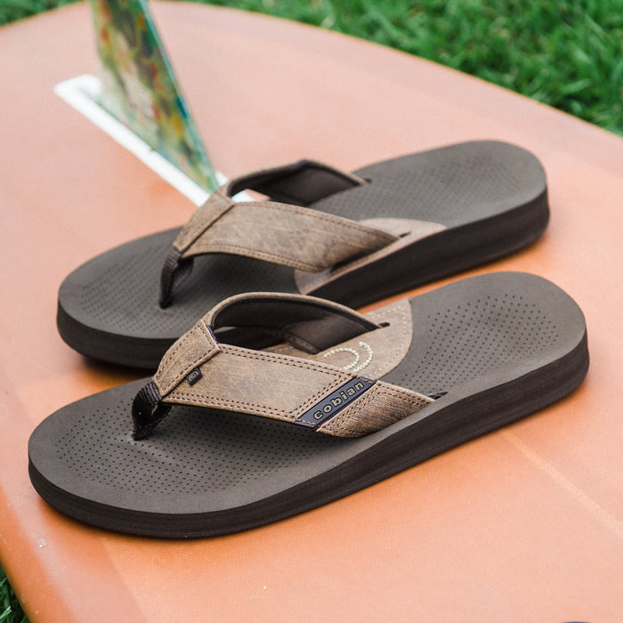 Cobian ARV 2 Java sandals on top of a surfboard #color_java