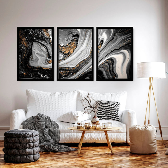 Three framed black and gold wall decor prints with swirling marble effect above a white sofa