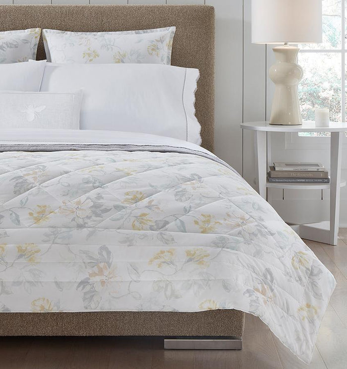 Brown bed with white quilted cotton bedding with a light yellow floral motif.