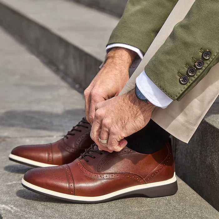 The Cap-Toe in Coffee Brown Leather worn by model wearing green jacket and light dress pants