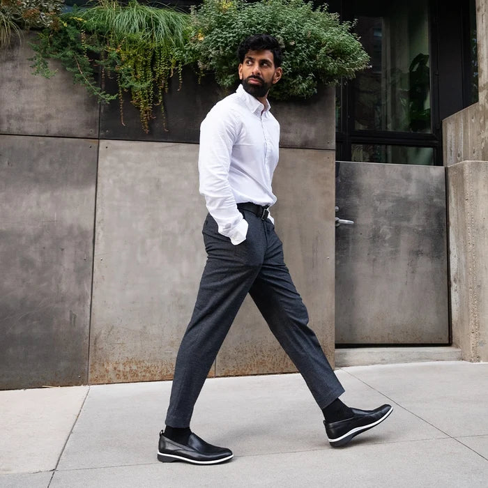 Model wearing dark gray dress pants paired with The Slip-On Onyx